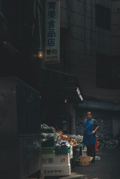身穿红色t恤和蓝色牛仔牛仔裤的男子在夜间站在食品摊位附近